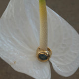 Gold ring with a green stone on a white flower petal